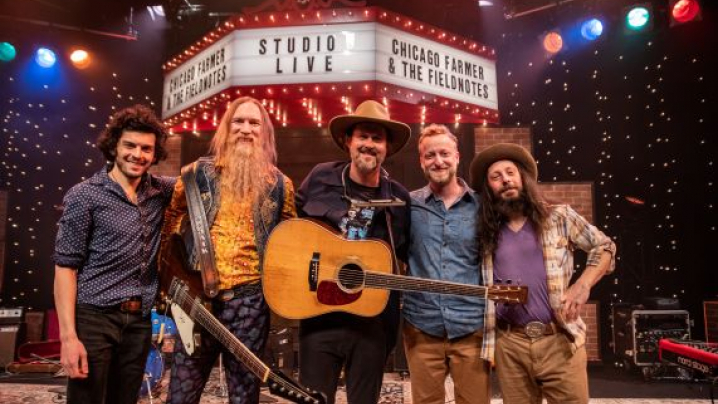 Five band members from Chicago Farmer standing on a stage.