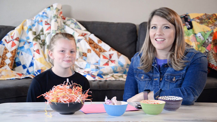 Abby and her friend sit in front of a small table with craft supplies.
