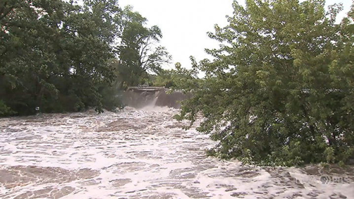 Floodwater rushes over the sides of a swollen river.
