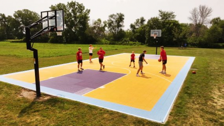 Five people playing basketball on a purple and yellow court