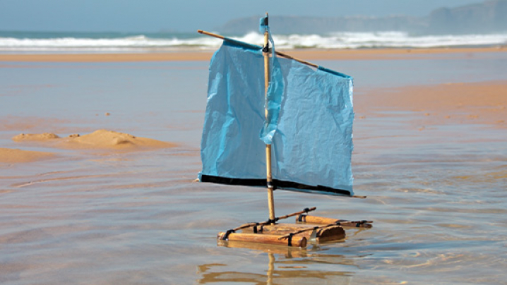 A DIY sailboat made of sticks and a paper sail.