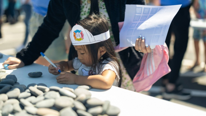 Little girl uses paint markers to create a kindness rock