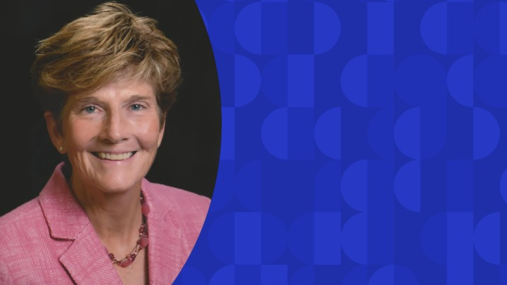 A woman smiling in a pink blazer.