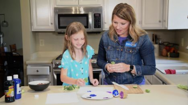 Abby and her friend paint with veggies.