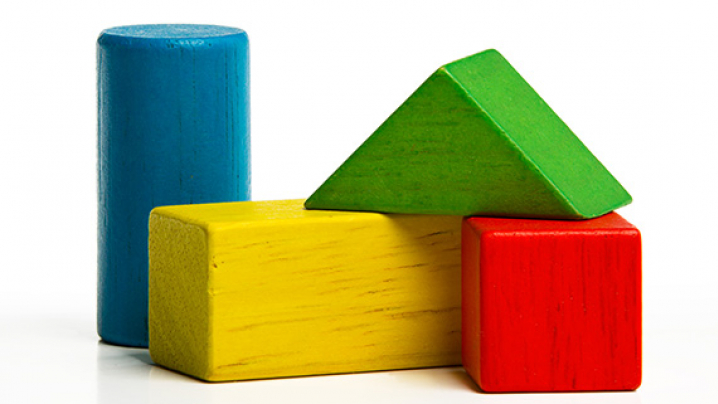 Colorful wooden blocks including a blue cylinder, yellow rectangle, red cube, and green triangle.