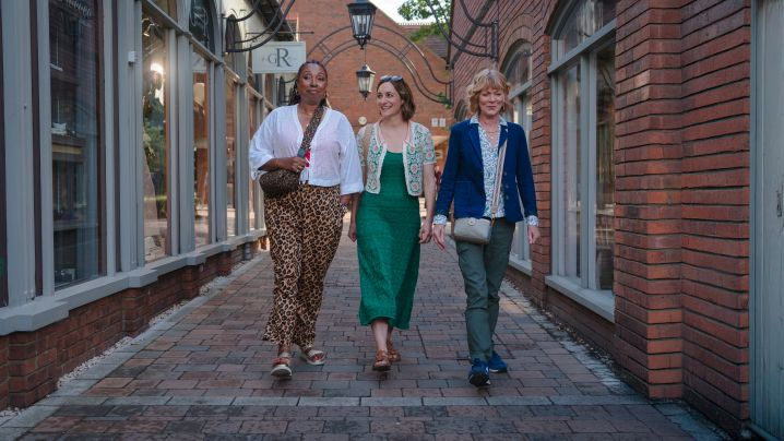 Three women, the main characters of the program, walking down an alleyway. 