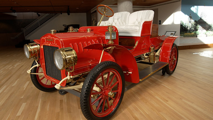 A fire engine red car with gold trim and prominent rounded headlights on either side of a decrative grill.