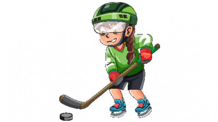 A young girl in a green hockey jersey and helmet plays hockey, holding a stick and bending down to strike a black puck.