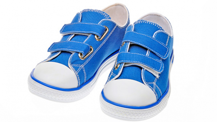 A pair of blue children's canvas shoes with white rubber toes and two Velcro straps.
