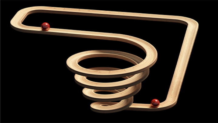 A wooden marble run with two red marbles, featuring a smooth, spiraling track against a black background.