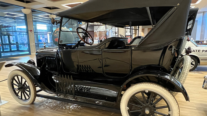 A vintage black automobile from the early 20th century with whitewall tires, displayed indoors in a museum.
