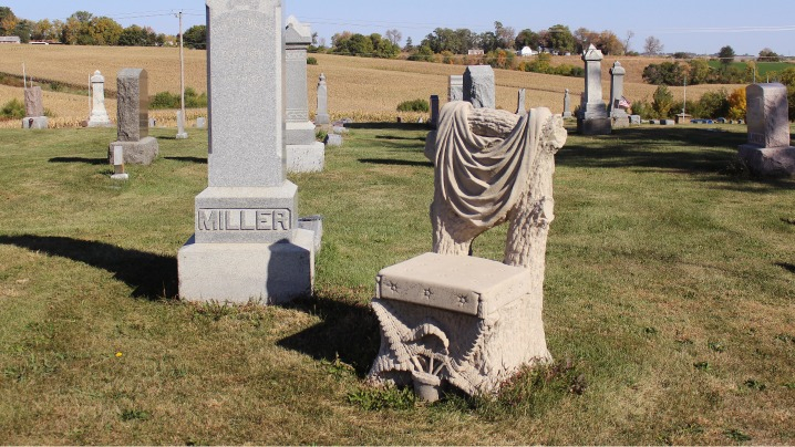 An intricately carved stone chair sits next to a Miller gravestone.