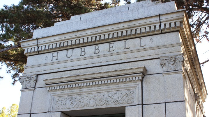 A white stone mausoleum with the name Hubbell engraved above the entrance.