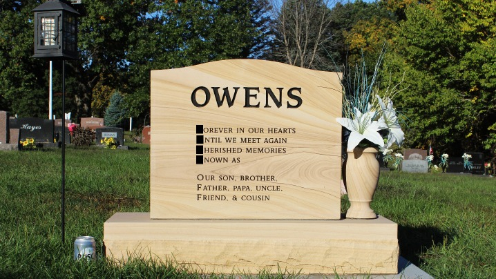 A cream-colored gravestone with the name Owens inscribed.