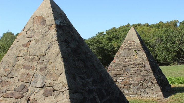 Two small stone pyramids in an open field of grass.