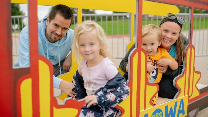 A family of four sitting in a wooden trolley.