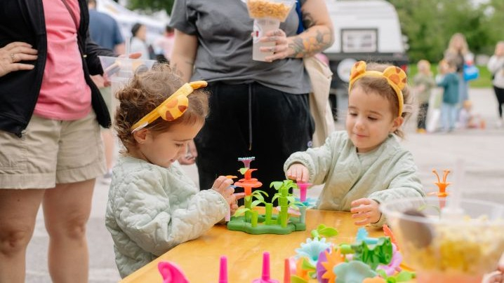 Two children with Daniel Tiger headbands on their head play with some learning flower toys.