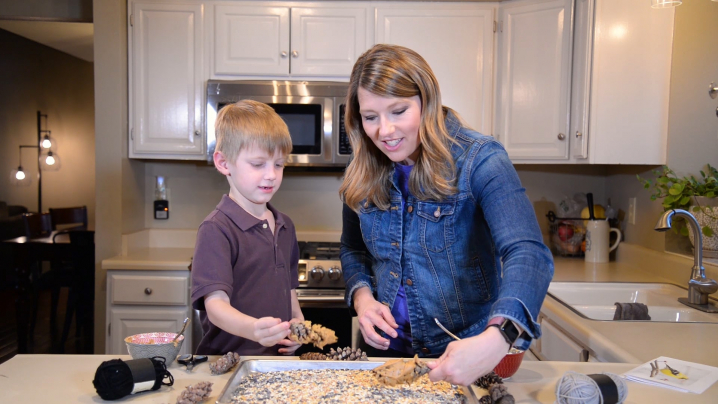 Host Abby Brown and a young boy creating a bird feeder craft together