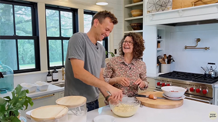 Kaleb Wyse and a woman make food in the kitchen. Both are laughing.