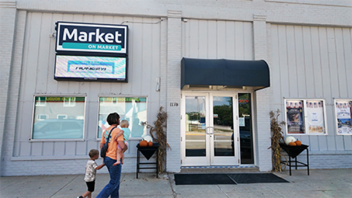 Market on Market's grocery storefront where a woman walks with her children up to the door.