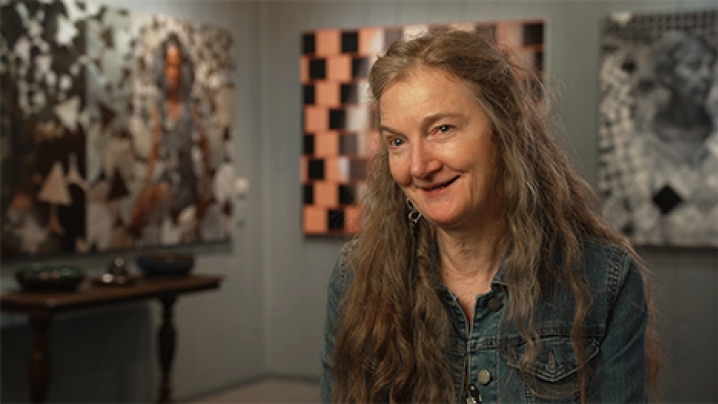 Painter, Rose Frantzen sits for an interview in front of several of her oil paintings.