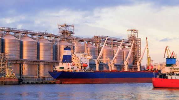 Bulk carrier ship in river port. Dry cargo grain elevator trade. 