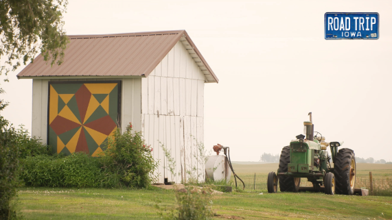 white barn with colorful paint on the side and a tractor parked out front