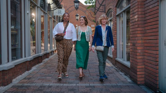 Three women, the main characters of the program, walking down an alleyway. 