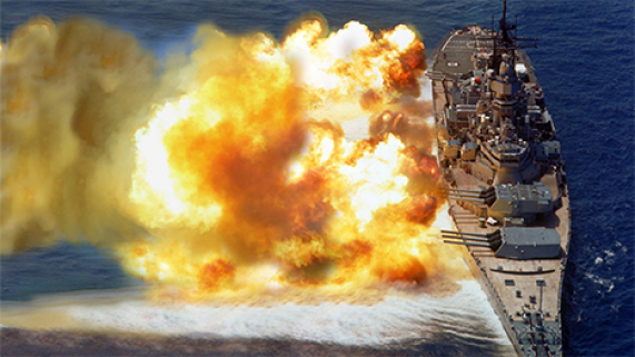 USS Iowa blasting its large guns...fireballs out the side of the ship from the blast of the guns.