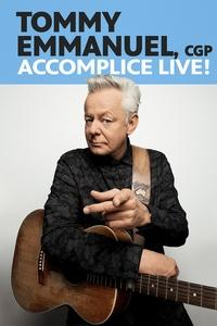 Tommy Emmanuel pointing at the camera while holding his guitar.