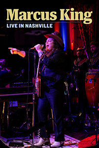 Marcus King sings on stage and points at the audience.
