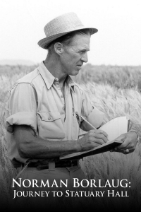 A man in a straw hat writing in a notebook in a wheat field.