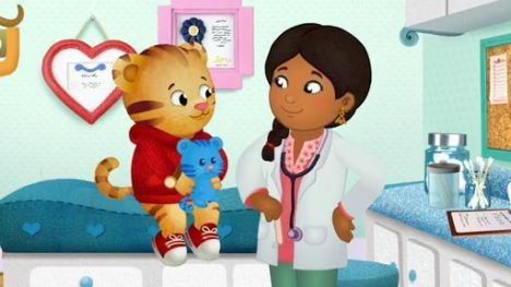 Daniel Tiger sits on an exam table speaking with the doctor.