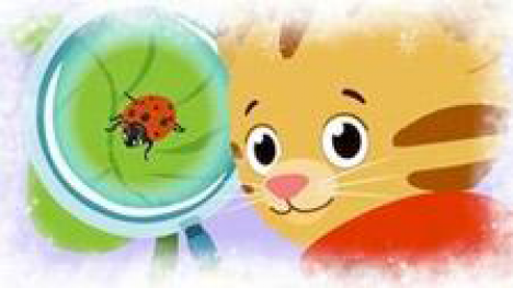 Daniel  Tiger looking at a ladybug through a magnifying glass 