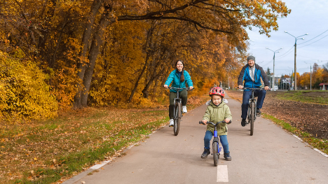 A family of three riding bikes on a cool fall day.