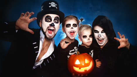 A spooky family of four with a jack-o'-lantern.