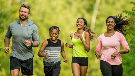 A family of four running outdoors.