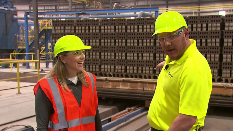 Two people wearing hard hats standing on the production floor of a brick factory.