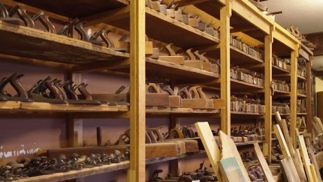 Floor to ceiling shelves along a wall with hundreds of hand planes resting on them.