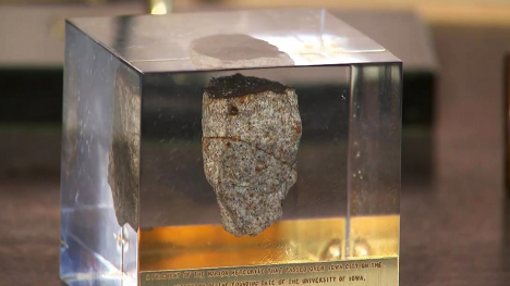 A fragment from a meteorite encased in resin and used as a paperweight.