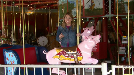 Abby Brown standing behind the pig ride on a carousel.
