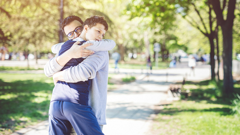 A father and son hugging in a park.