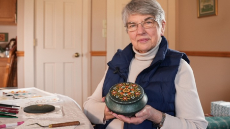 Rosemaling artist Ruth Green holding a finished piece