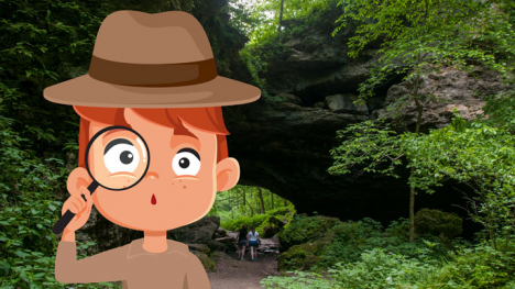 Boy holds a magnifying class at a caves site