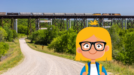 Girl with blond hair and glasses stands beside a gravel road with a high railroad bridge in the background