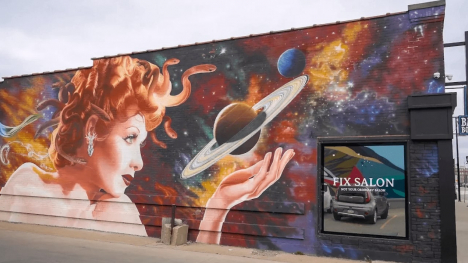 Building mural featuring a Medusa-like woman holding a ringed planet in her hand