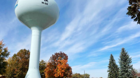 A water tower in a town on a fall day.