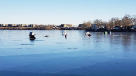 A frozen lake with five ice fishing tents on it.