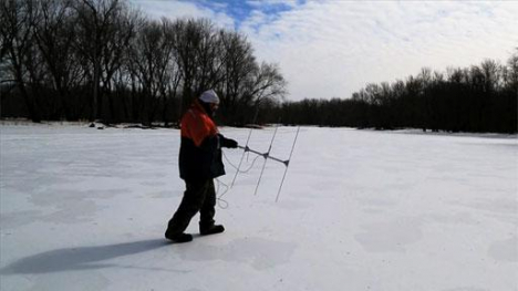 Image of man with radio antenna walking on frozen lake.