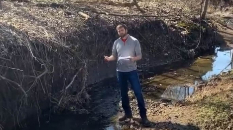 Image of man standing next to a stream bank.